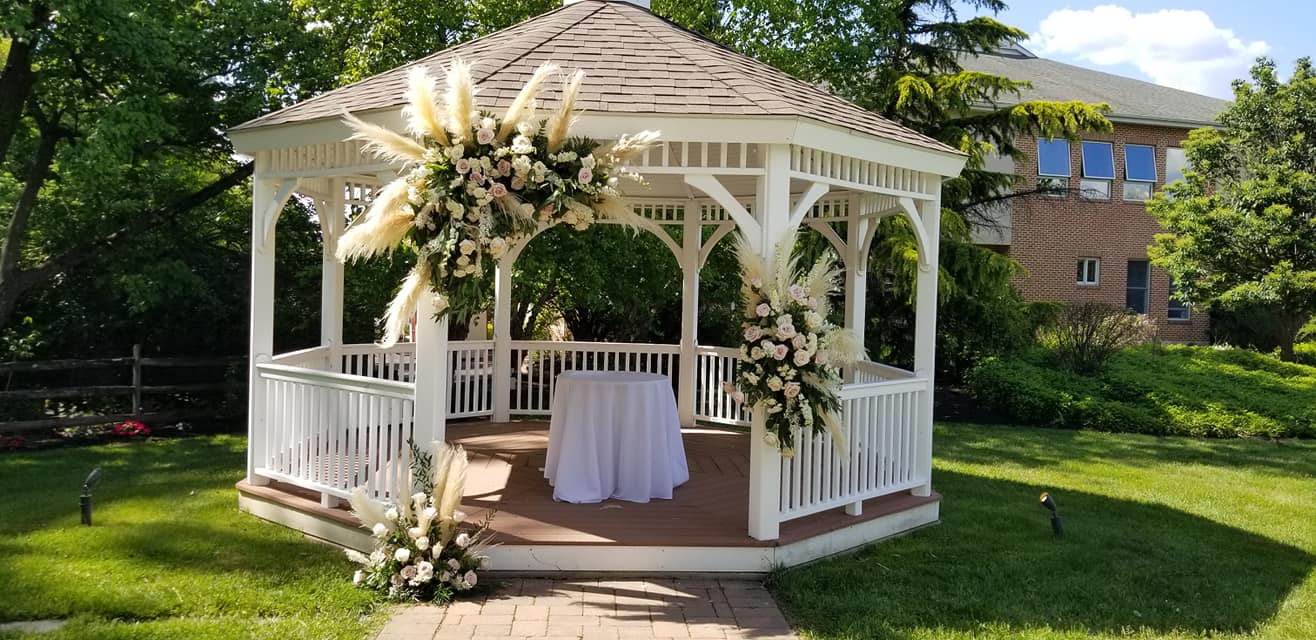 White garden gazebo decorated with florals for outdoor wedding ceremony